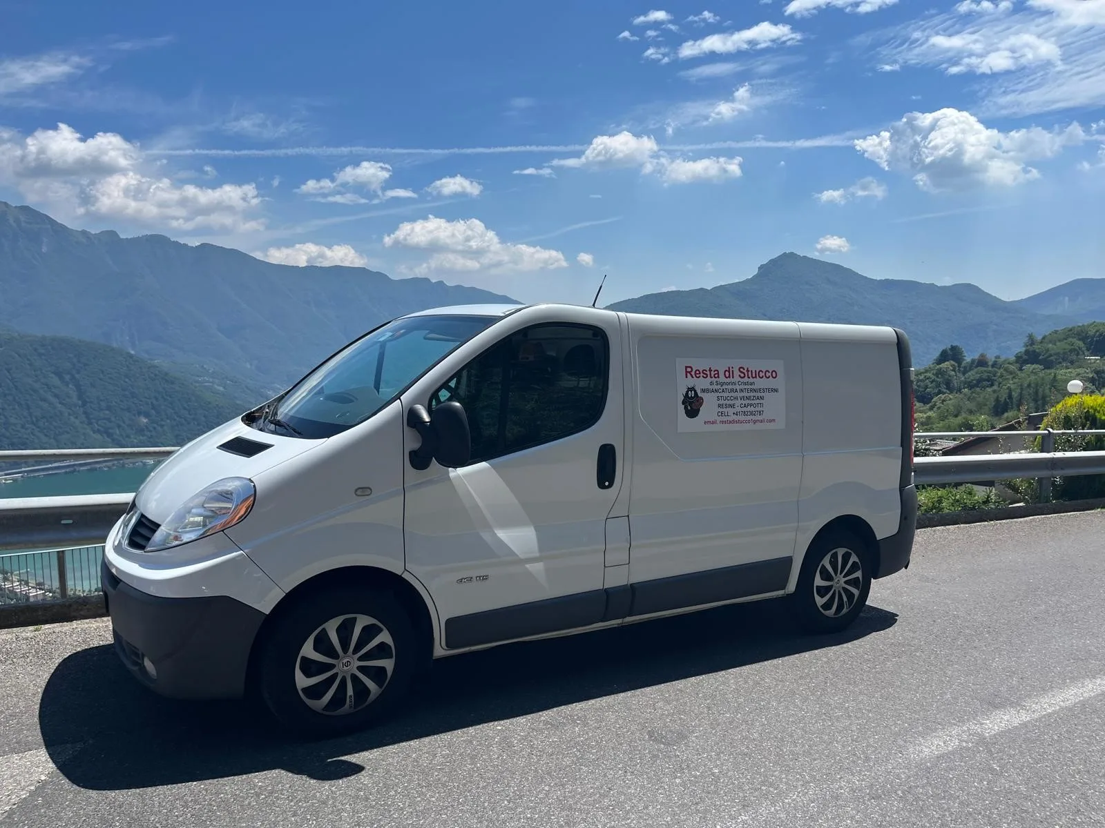 Il furgone bianco di Resta di Stucco con la scritta «Imbiancatura interni/esterni, stucchi veneziani, resine, cappotti», parcheggiato su una strada panoramica sopra il lago
